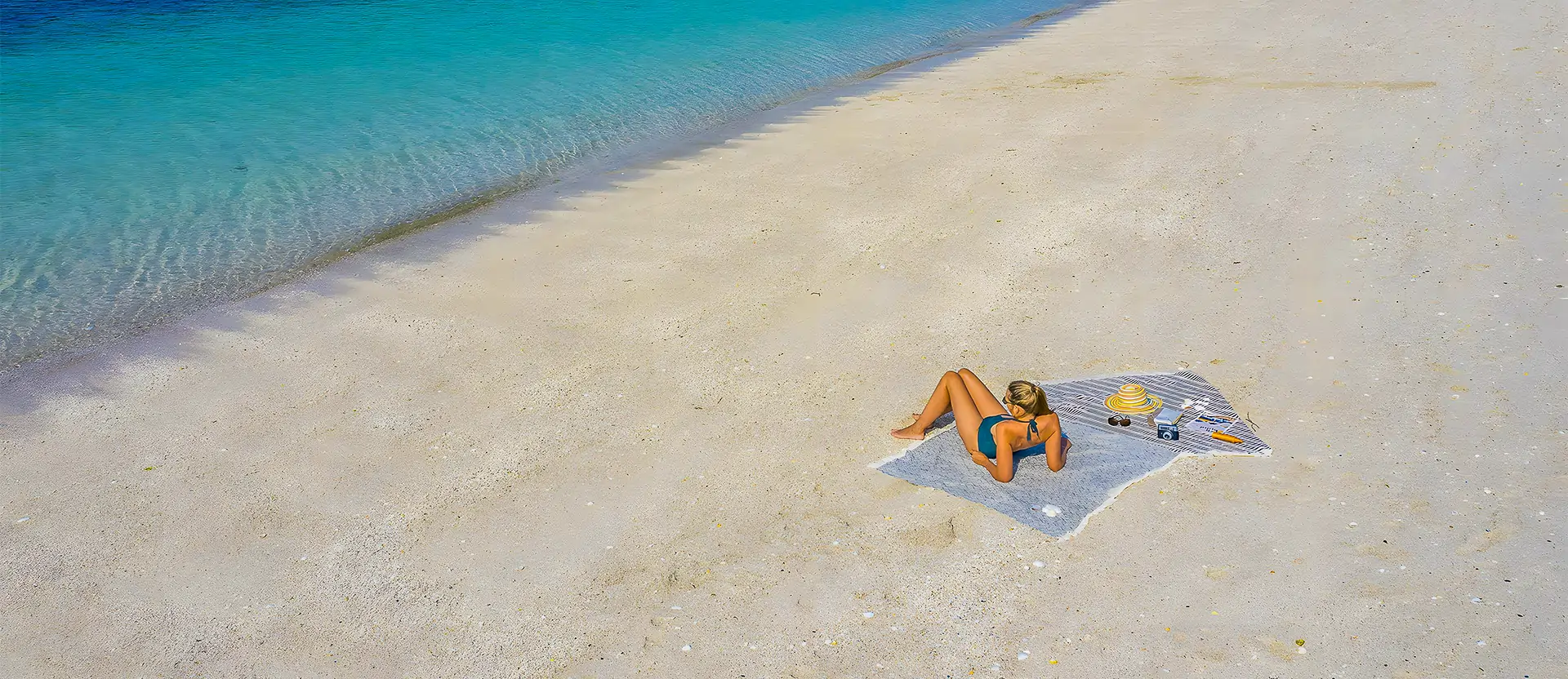 Vacancière allongée sur le sable blanc de la plage de la Belle Étoile, face au camping Le Cabellou Plage à Concarneau